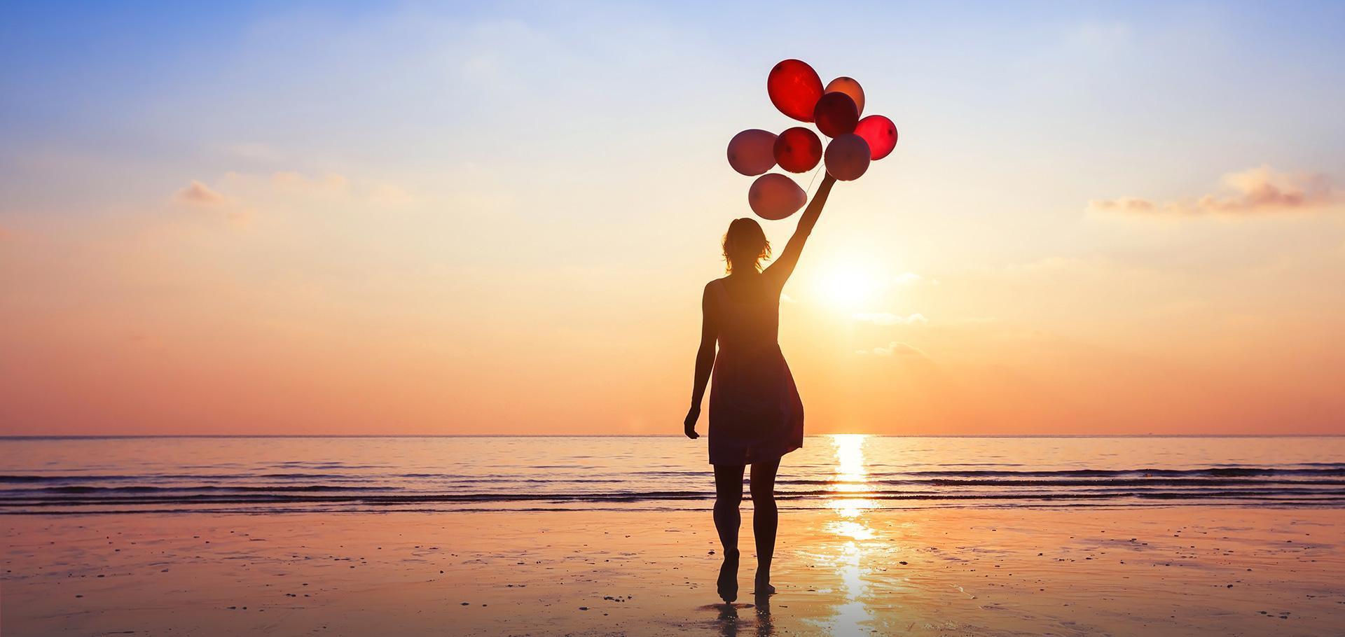 Slajd #1 - kobieta trzymająca balony na plaży